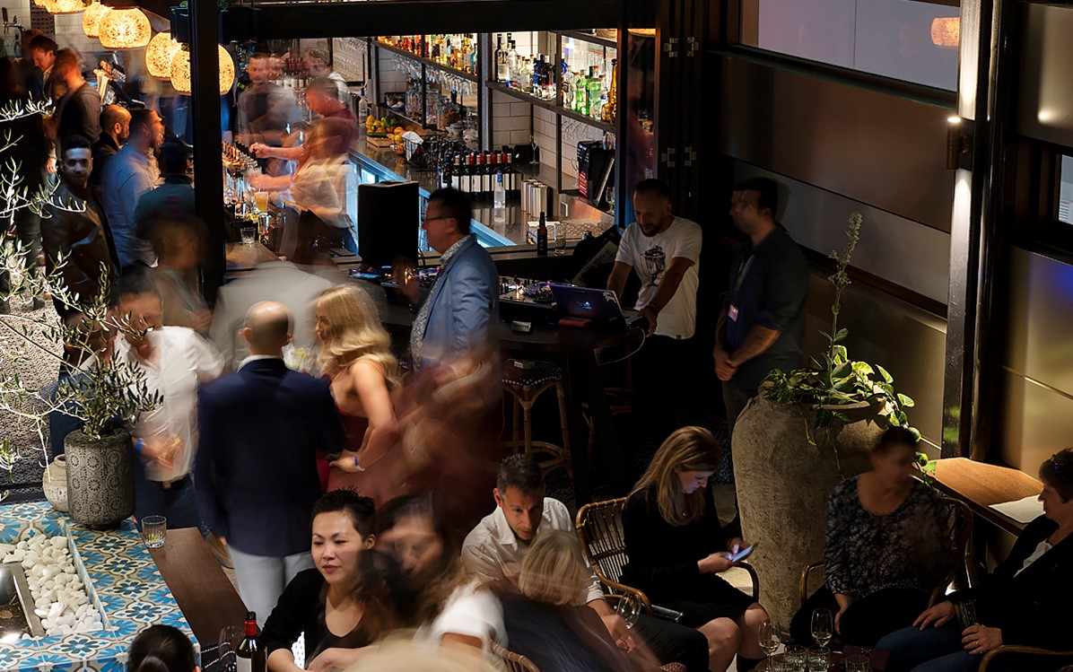 A restaurant and bar interior is full of people and movement.