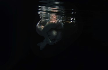 Image of a person curled up underwater 
