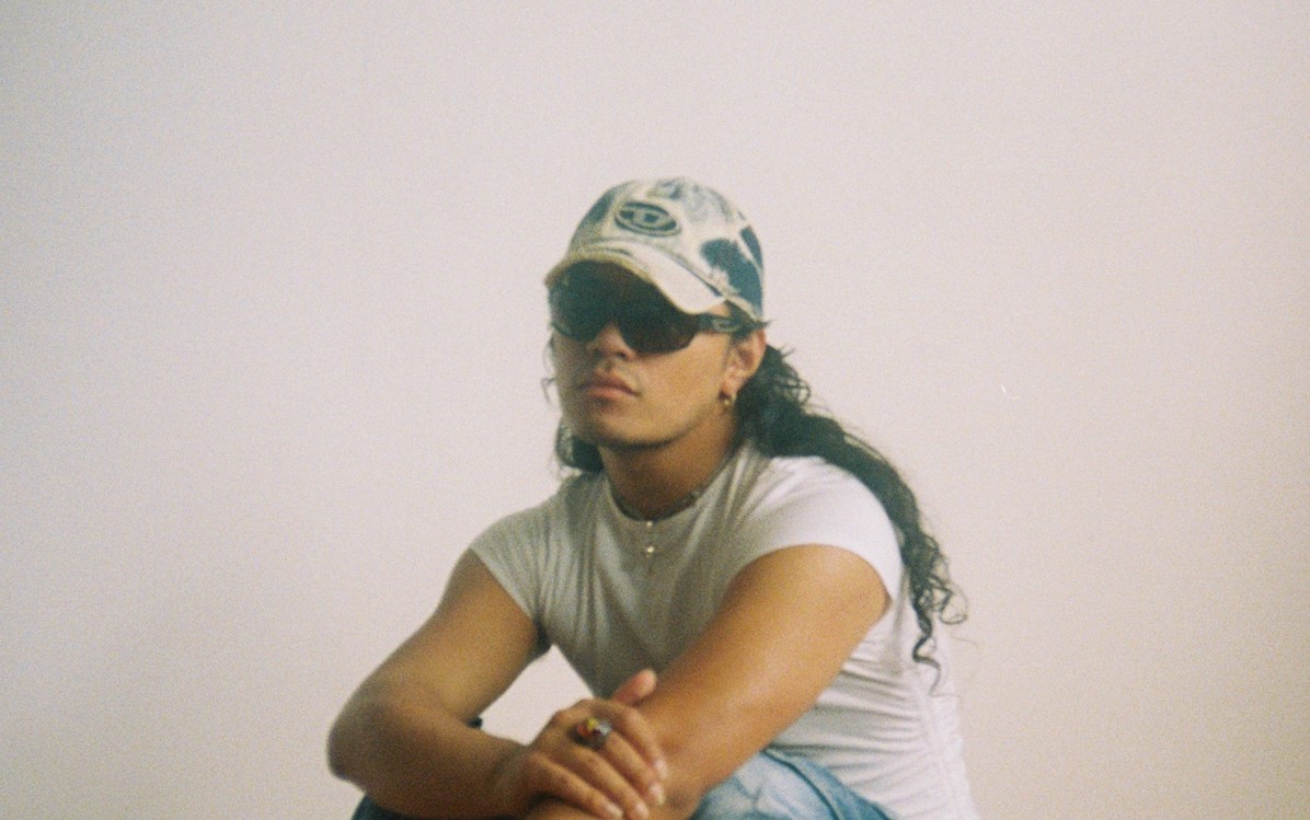 A film photograph of Julai crouched down in front of a white wall
