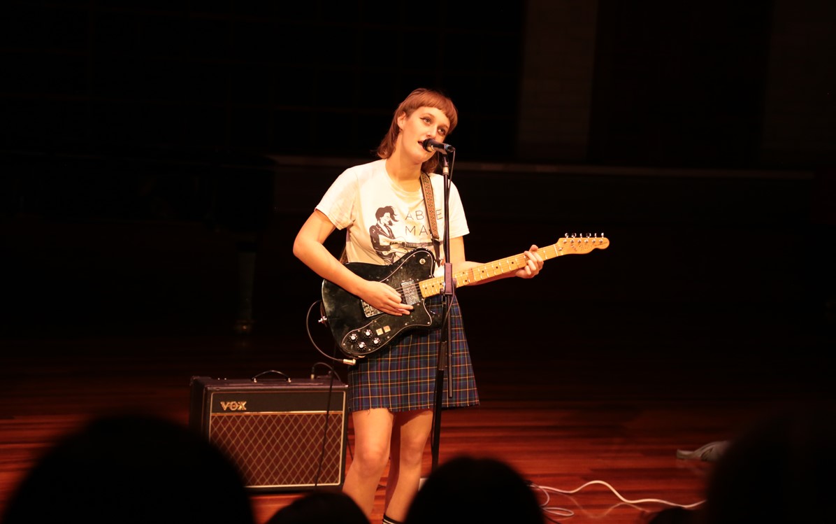 Image of woman playing guitar and singing on stage