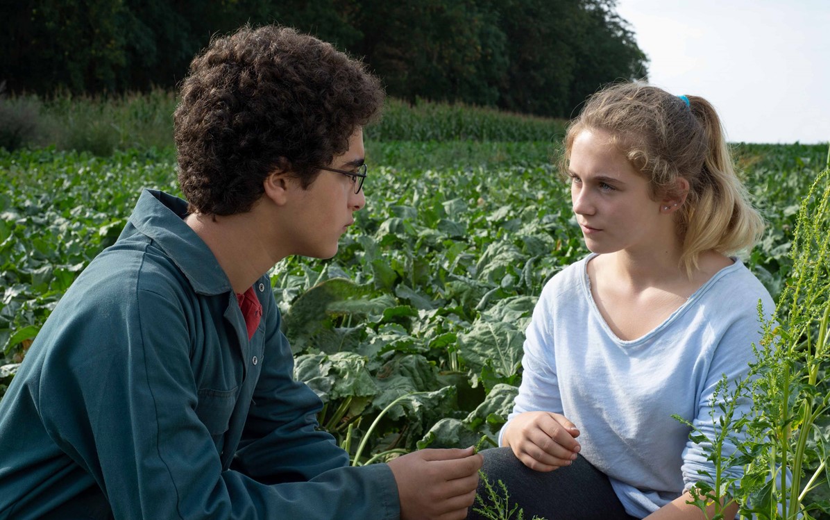 Image of Ahmed sitting in a field with a girl in ''Young Ahmed''