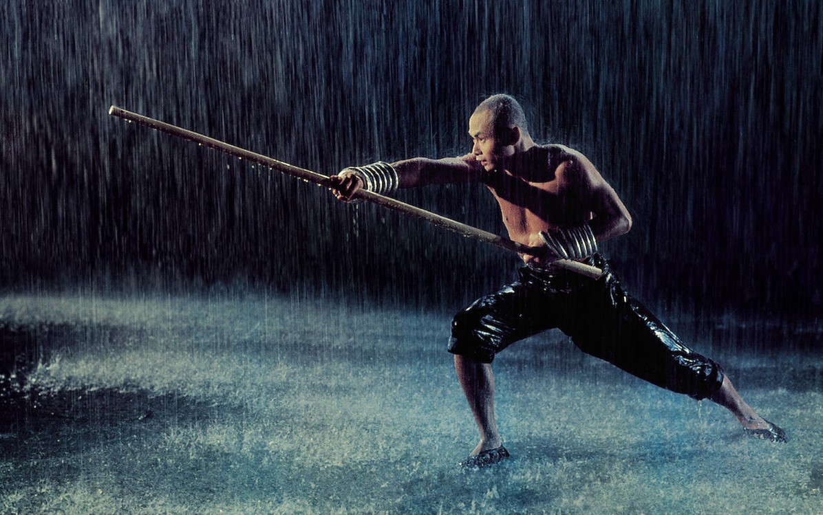 Image of man in the rain holding a long pole, from "The 36th Chamber of Shaolin''