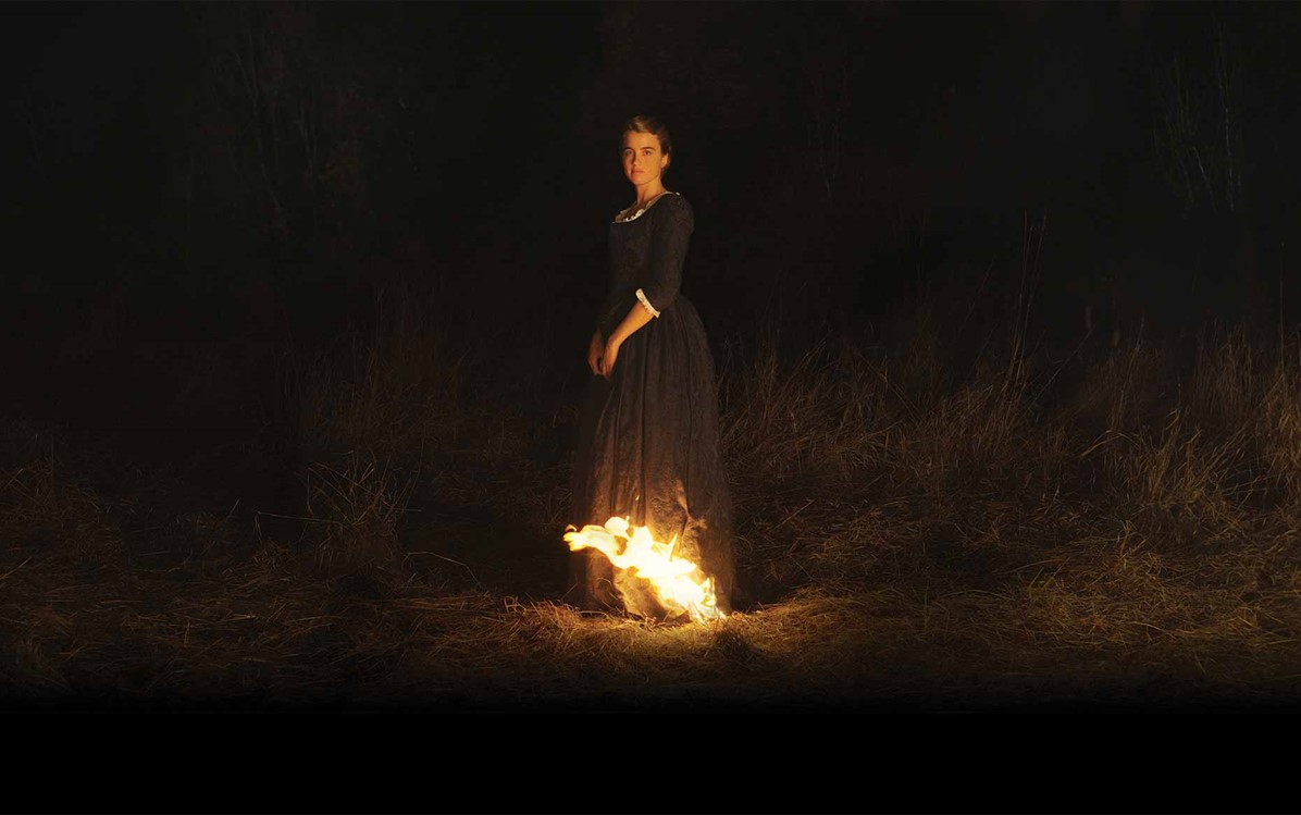 Image of a lady standing in a dark field with fire at the bottom of her dress