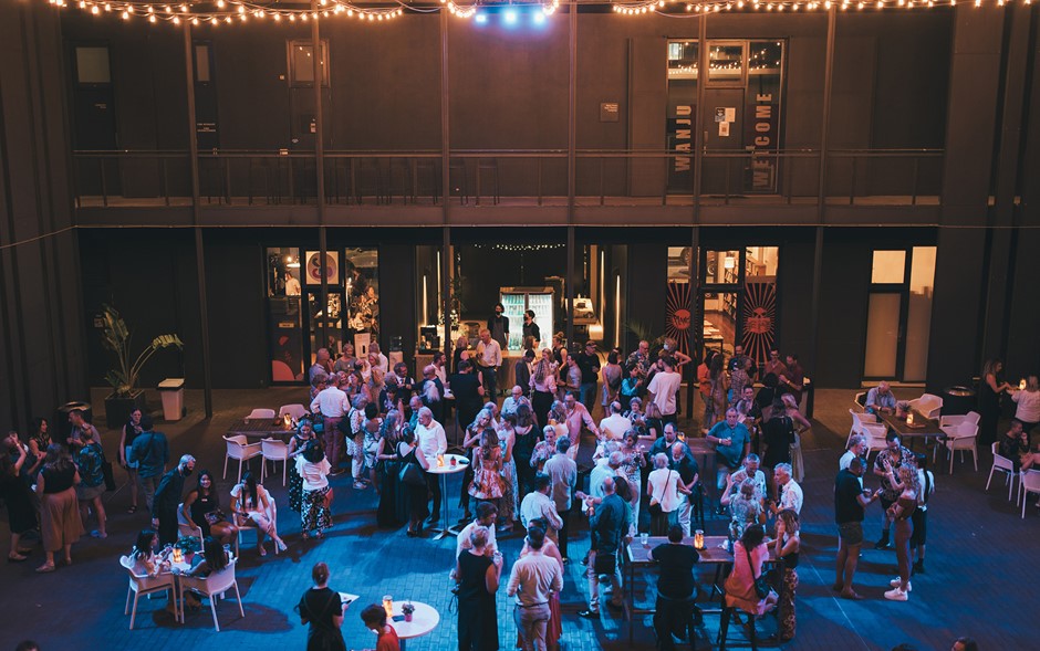 A group of people congregate around cocktail tables in the State Theatre Centre Courtyard