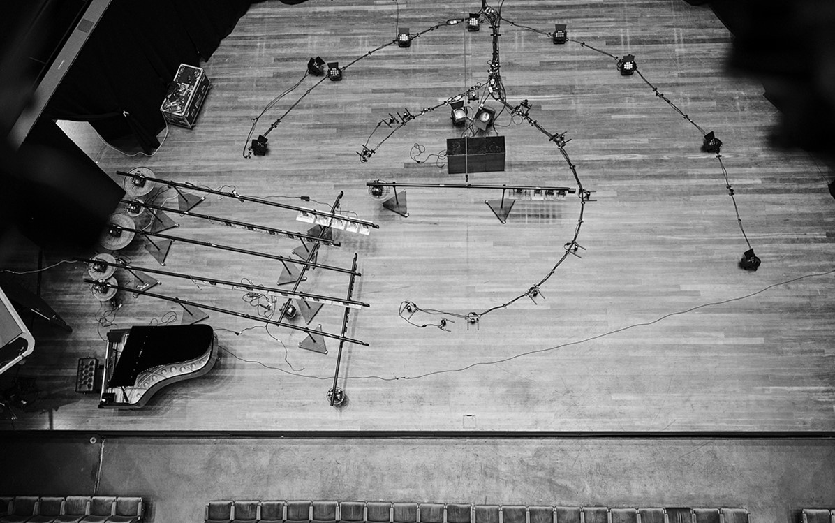 A black and white image of a birds eye view of a stage being set up for a production. Equipment is laid out over the stage.  Credit Duncan Wright