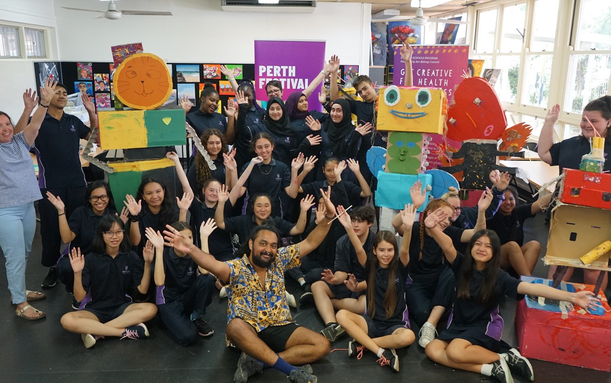 Image of kids and teachers smiling with their hands in the air 