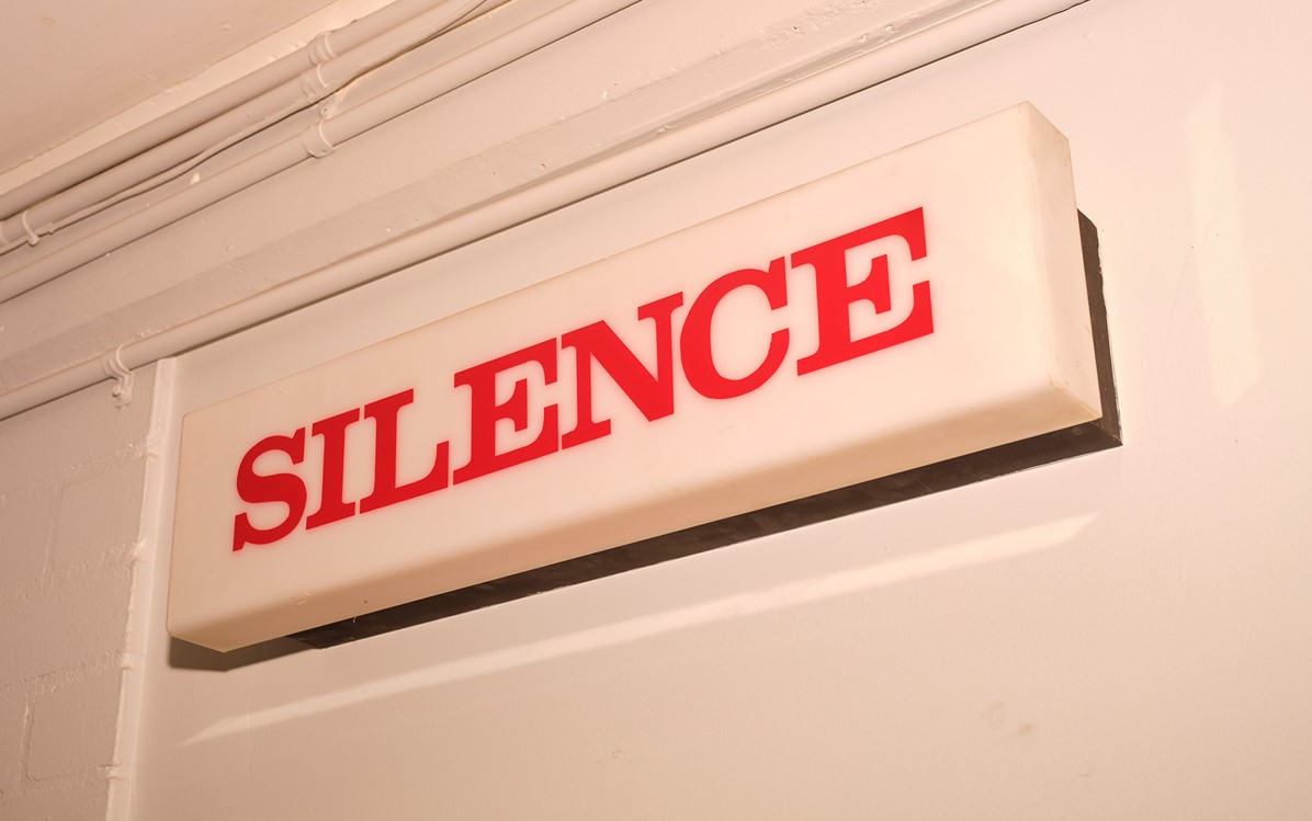 A white 'Silence' sign with red lettering on a white wall.  Credit Duncan Wright