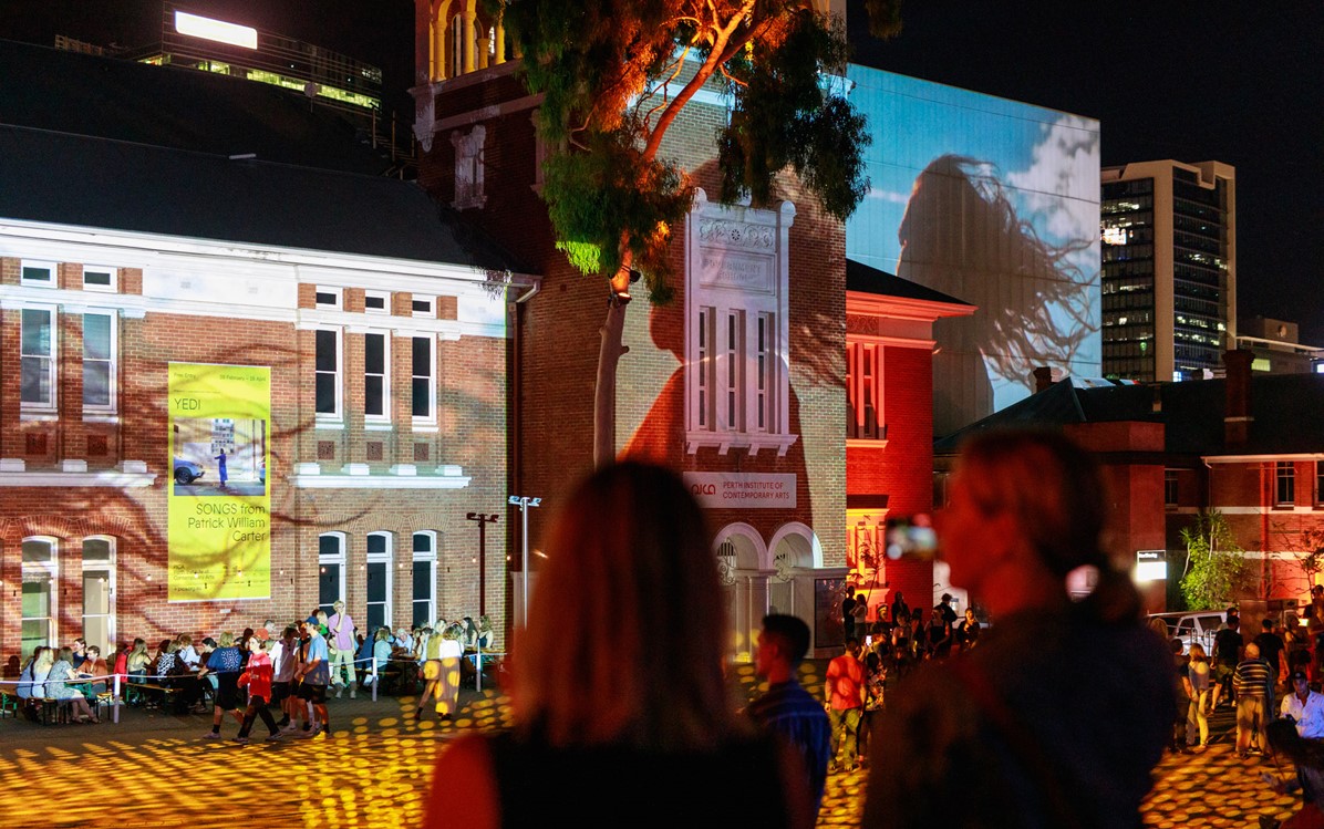  Projections light up the Perth Cultural Centre as bystanders watch. 