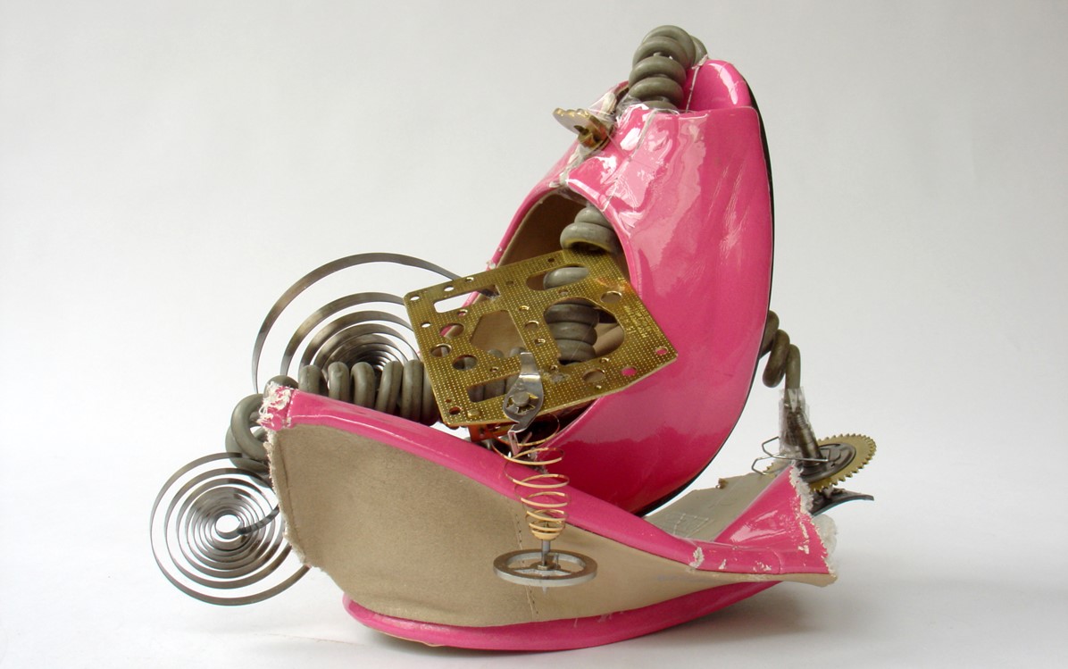 Image of: telephone wire, coils and metal cogs have been stuffed inside a cut in half pink open toed shoe.