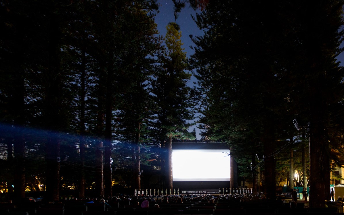 Lotterywest Films opening night 2021. Taken from the back of the cinema at night, the screen is white but lit up.