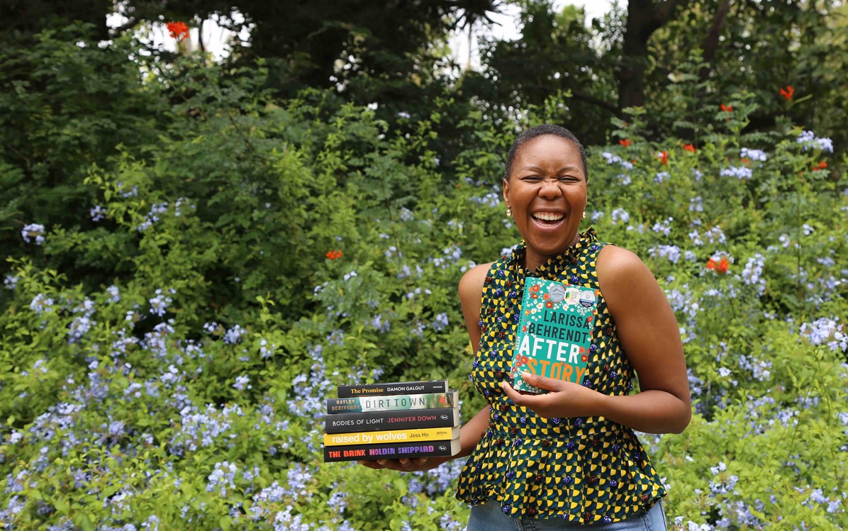 Sisonke is laughing and holding a pile of books